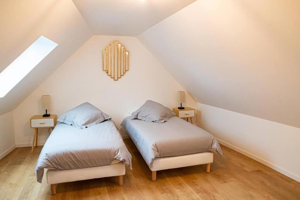 Un dormitorio abuhardillado con dos camas y dos lámparas. en Gîte Les Camélias 2 chambres, 2 salles de bains, en Villers-Cotterêts