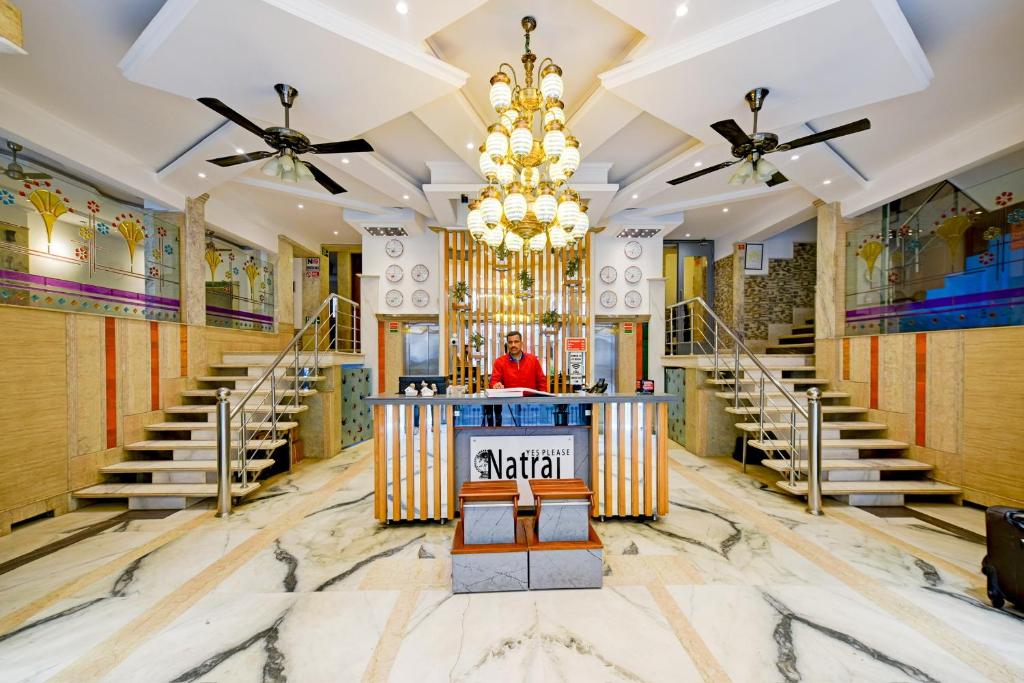 a man standing at a counter in a room with stairs at Hotel Natraj Yes Please New Delhi in New Delhi