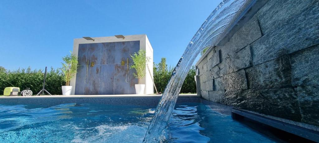 CasaKadd001Luxury Heated Pool Garden PatioBarbeque في Civé: نافورة مياه في مسبح بجانب مبنى