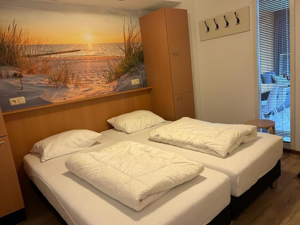 - 2 lits dans une chambre avec une photo de la plage dans l'établissement Appartement De Wadloper, Resort Amelander Kaap!, à Hollum