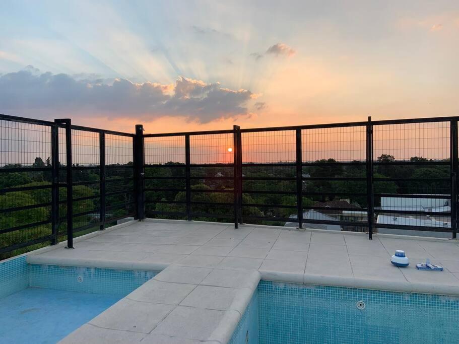 una piscina en un balcón con la puesta de sol en el fondo en Golf en Rosario