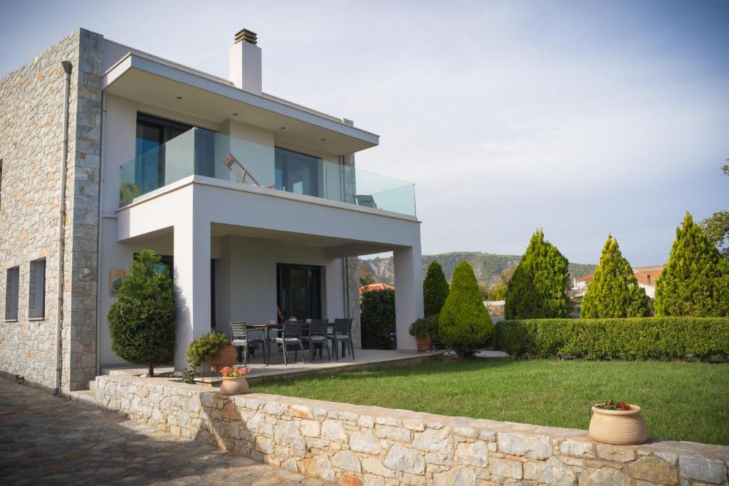 une maison blanche avec un mur en pierre dans l'établissement Villa Aggemari, à Apidias Lakos