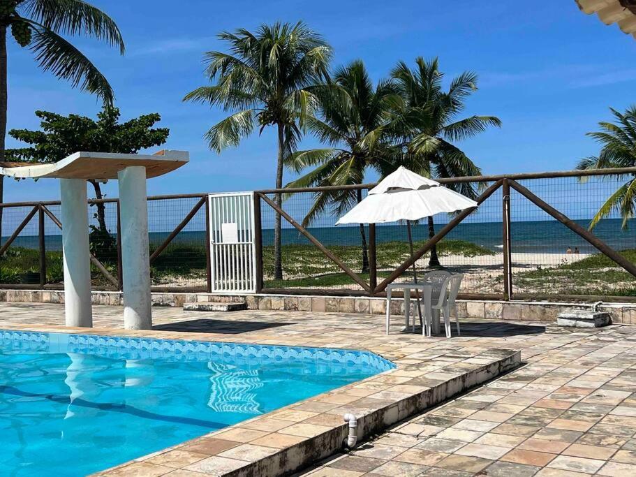 - une piscine avec un parasol, une table et un parasol dans l'établissement Apartamento frente ao mar na praia do guaibim., à Guaibim