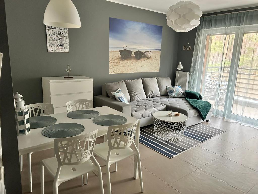 a living room with a couch and a table and chairs at Apartament Przy Lesie in Międzywodzie