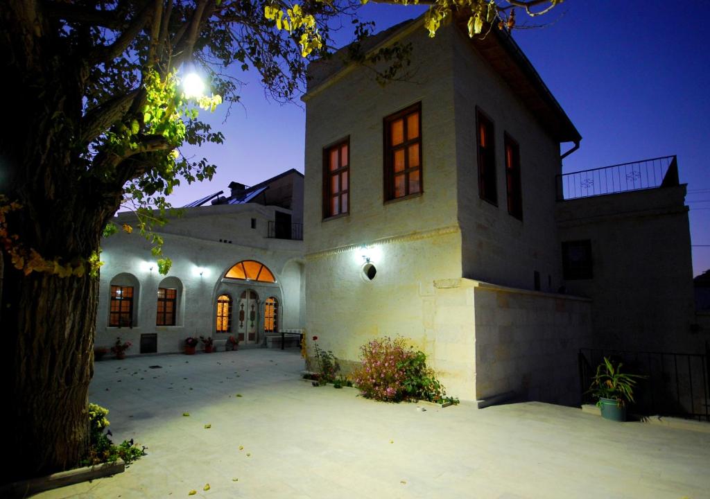 a large white building with a tree in front of it at Upper Greek House in Mustafapaşa