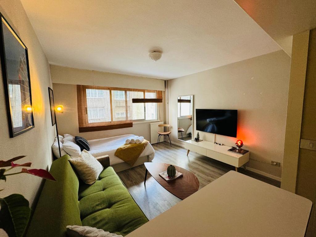 uma sala de estar com um sofá verde e uma cama em Loft Azom em Vigo