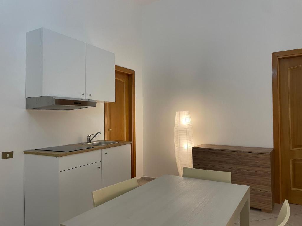 a white kitchen with a table and a sink at da zia Emanuela in Ottaviano