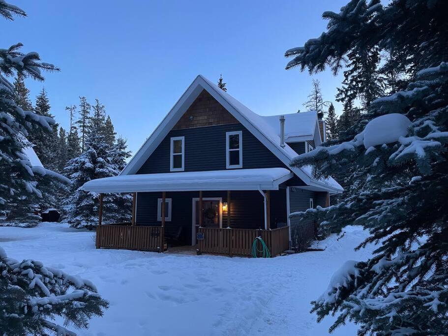 a house in the snow with snow covered trees at Charming Cabin in the Mountains-HOT TUB! in Nordegg