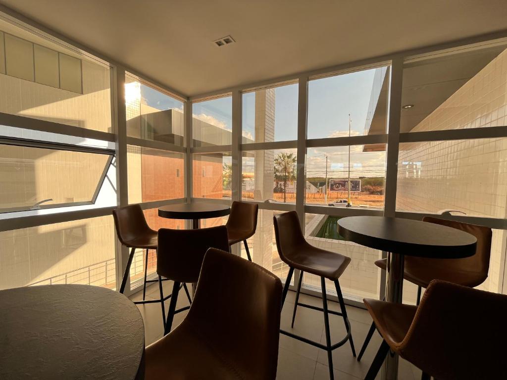 eine Gruppe von Tischen und Stühlen in einem Zimmer mit Fenstern in der Unterkunft Studio Moderno Westfit in Mossoró