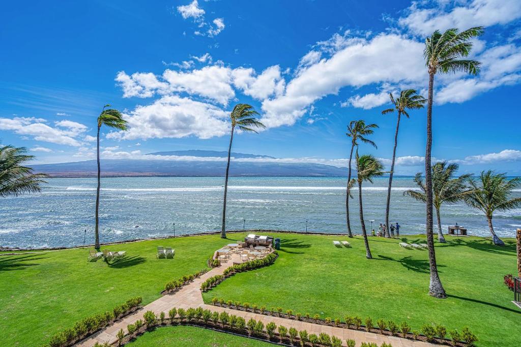 a field of grass with palm trees and the ocean at Maalaea Kai 311 - Direct Ocean Front, Split AC in Wailuku