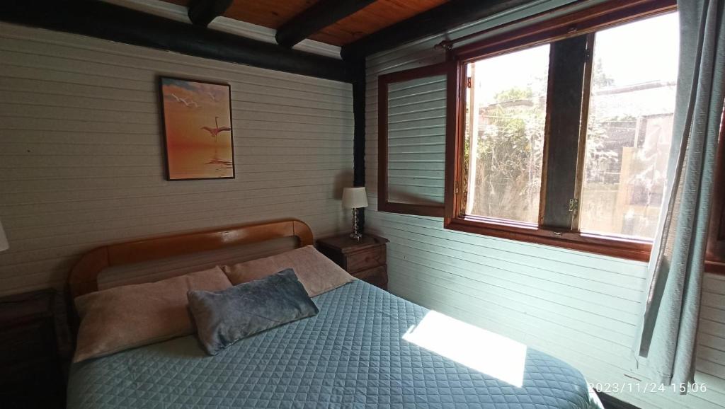 um quarto com uma cama e uma janela em Villa Anita Piriapolis em Piriápolis