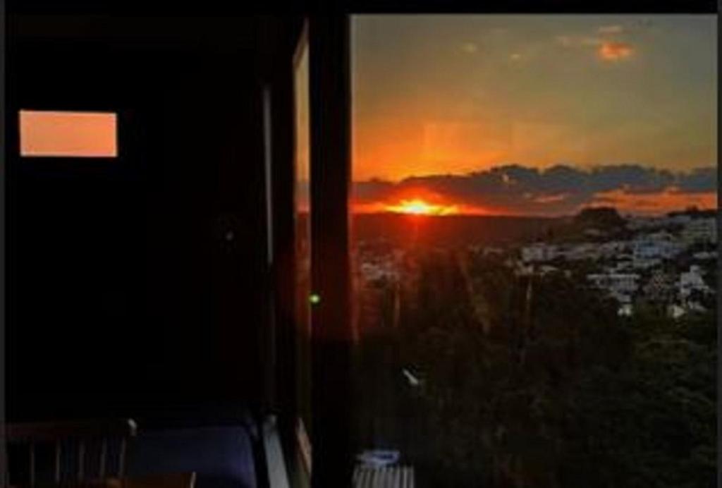 a view of a sunset from a room with a window at senahahausub03 in Yomitan