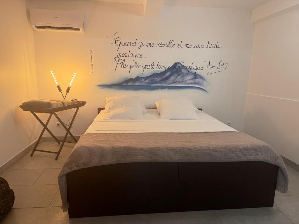 een slaapkamer met een bed met een schilderij aan de muur bij Villa de 5 chambres avec vue sur la mer piscine privee et jardin clos a Le Carbet a 1 km de la plage in Le Carbet