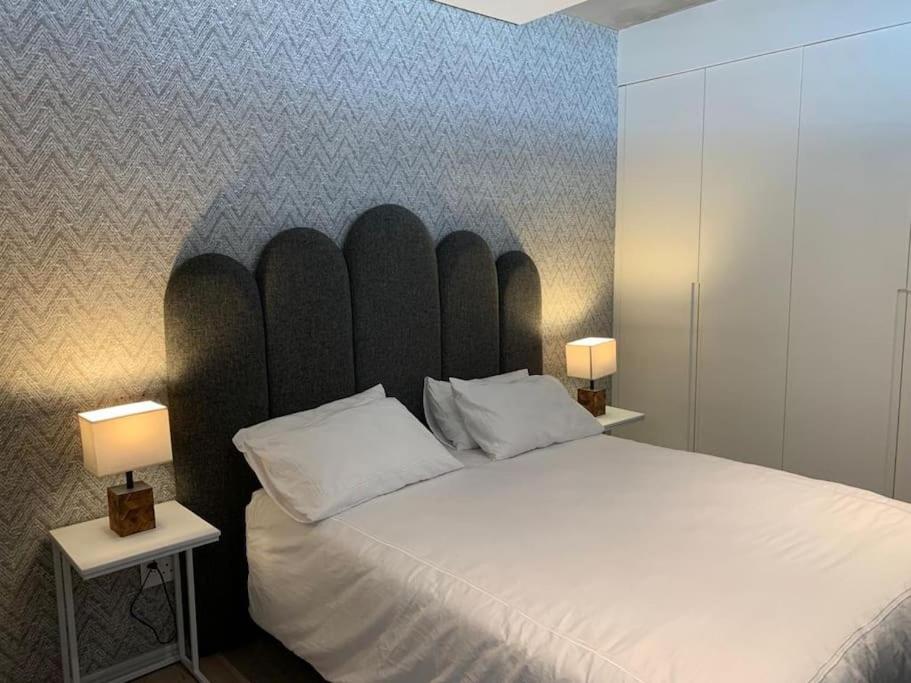 a bedroom with a large white bed with two lamps at The Quarter Mountain View Haven at Waterkant in Cape Town