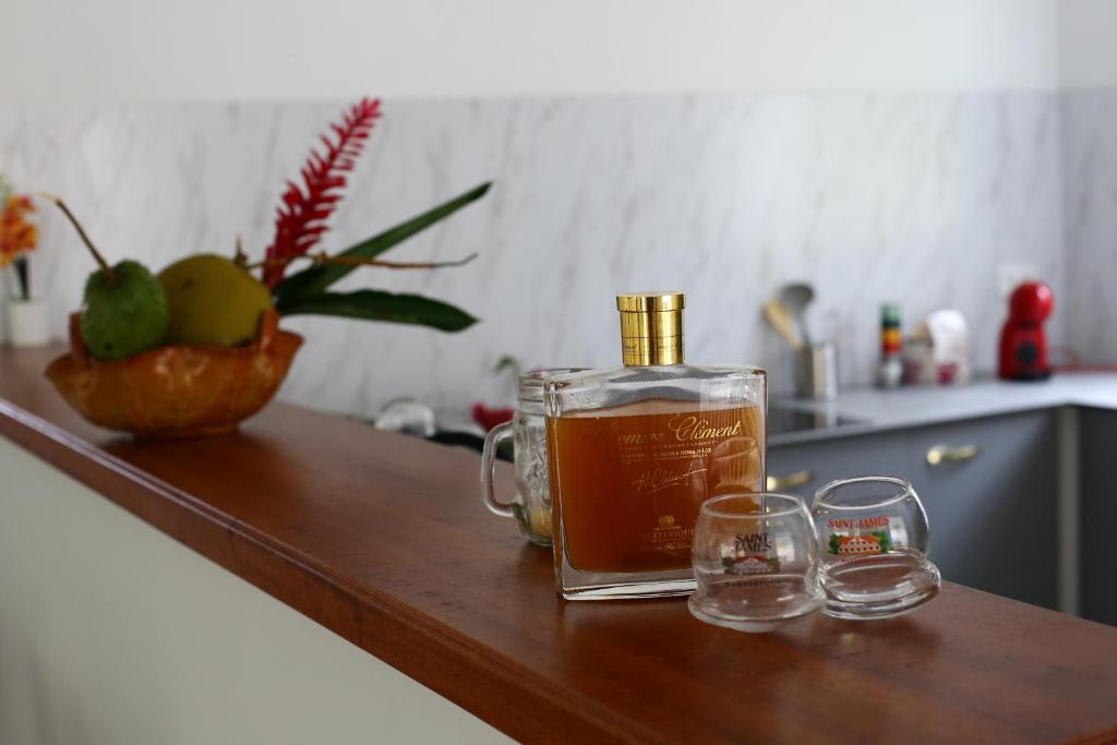 a bottle of whiskey and two glasses on a counter at Villa les MAHOGANYS in Rivière-Salée