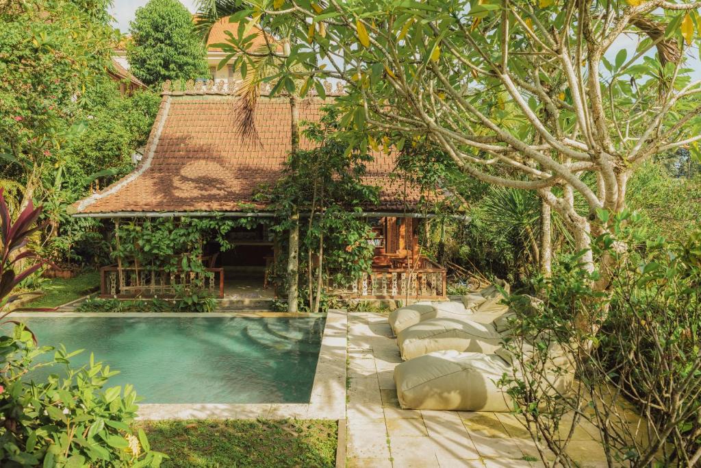 a house with a swimming pool in a garden at Villa Lumbung in Ubud