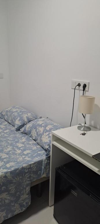 una cama y un escritorio con una lámpara al lado en La Marina, en Alicante