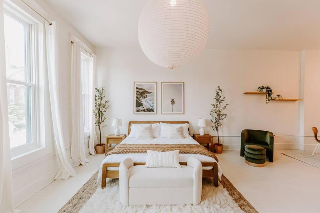 a white bedroom with a bed and a chair at East Main Lofts - Coastal 201 in Madison