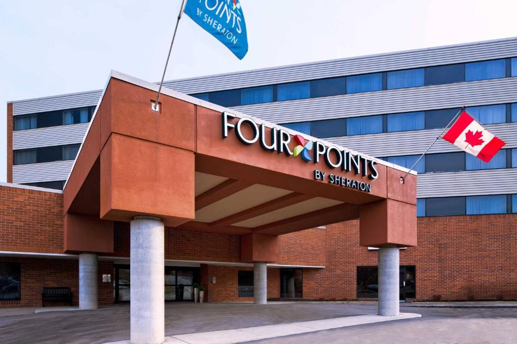 eine Vorderansicht eines Vier-Punkte-Gebäudes mit zwei kanadischen Flaggen in der Unterkunft Four Points by Sheraton Edmundston Hotel & Conference Center in Edmundston