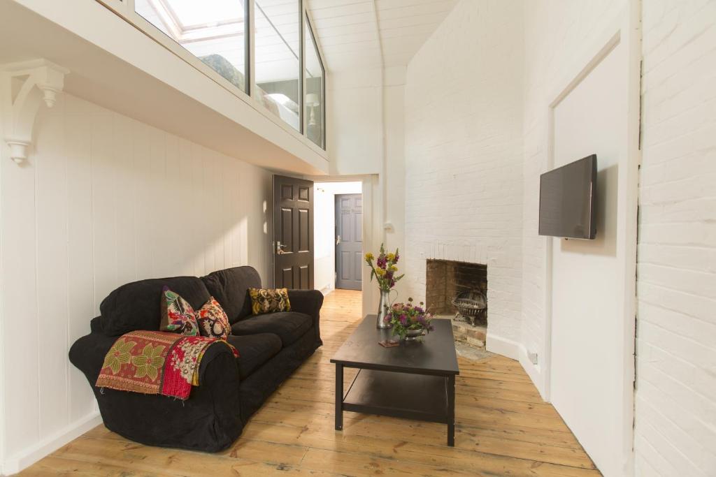 a living room with a black couch and a fireplace at Two Bare Feet in Winchester