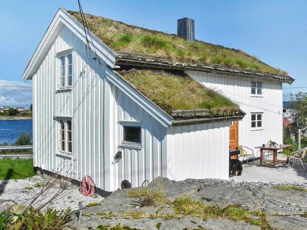 Casa blanca con techo de hierba y mesa en Holiday home Averøy VII, en Averoy