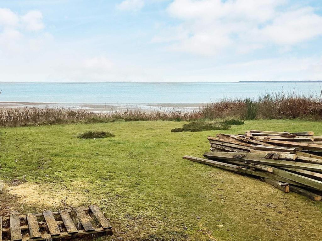 una pila de madera sentada en la hierba cerca del océano en Holiday home Esbjerg V XI en Esbjerg