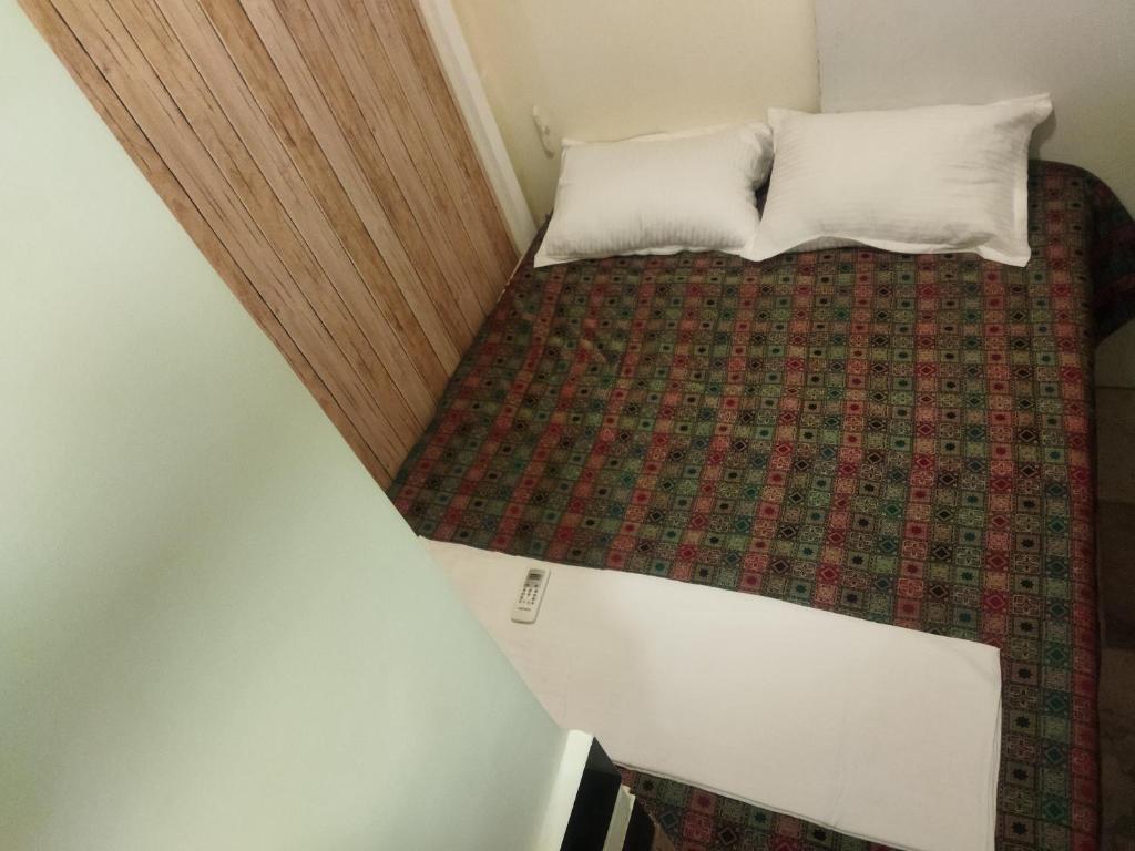 a small bed with two pillows on top of it at Near Airport AC Double Room at a Budget Inn in Mumbai