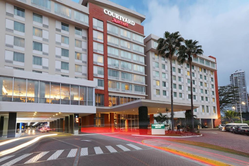 a hotel building with a palm tree in front of it at Courtyard by Marriott Panama Multiplaza Mall in Panama City