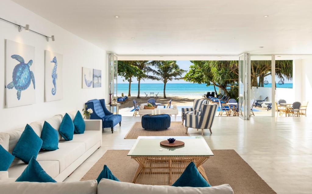 a living room with a white couch and blue pillows at Vis Ta Vie -Thema Collection in Mirissa