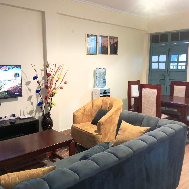 sala de estar con sofá, sillas y mesa en Miller's Haven, en Kakamega