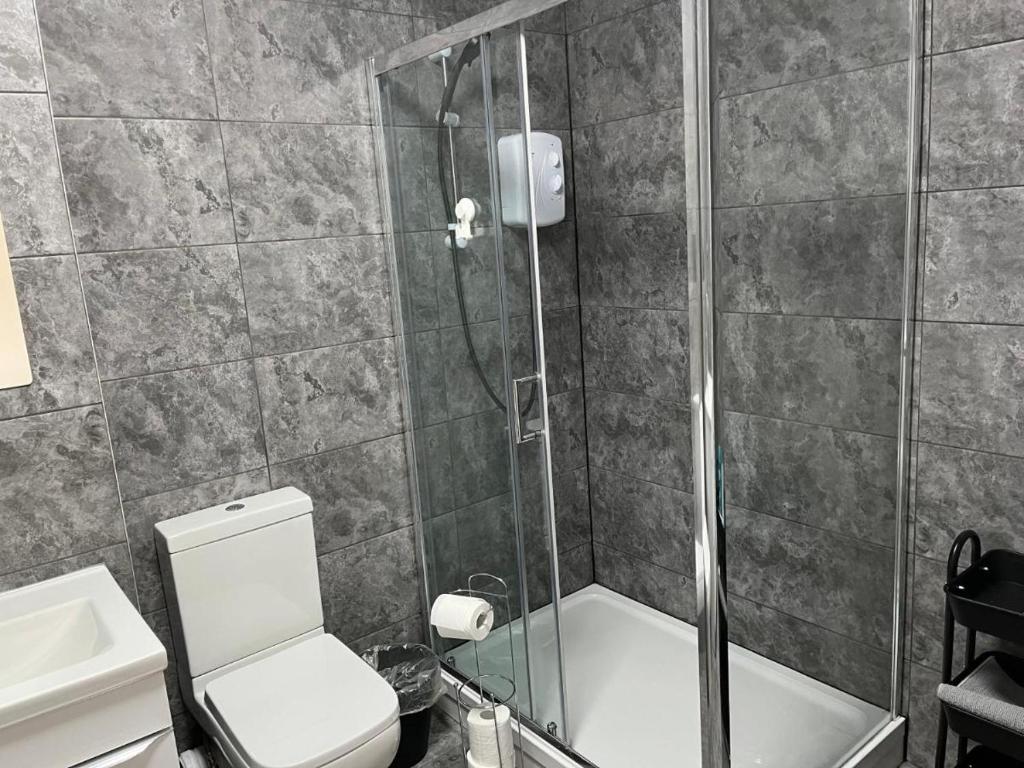uma casa de banho com um chuveiro, um WC e um lavatório. em Morden Apartment in City Centre em Manchester
