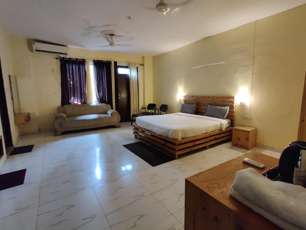 a large bedroom with a bed and a couch at HOTEL THE CORBETT VANSH in Rāmnagar
