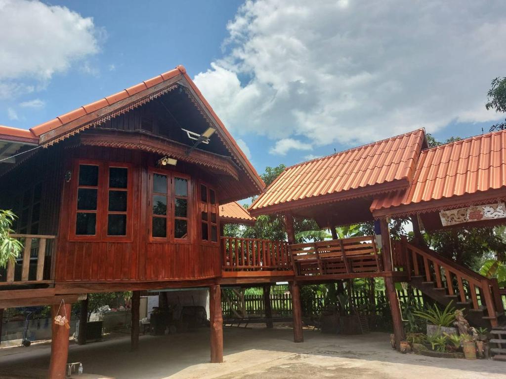 a large wooden house with a large deck at Duangmanee Homestay in Ban Si Kaeo