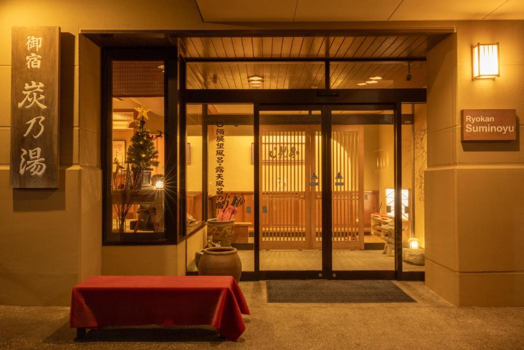 una entrada a un edificio con una mesa roja delante en Suminoyu, en Yamanouchi