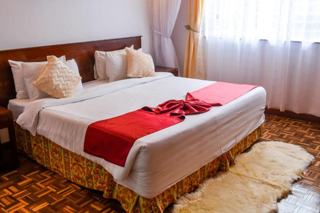 a bedroom with a large bed with a red bow on it at MOONLIGHT HOMES EAST CHURCH ROAD Westlands in Nairobi