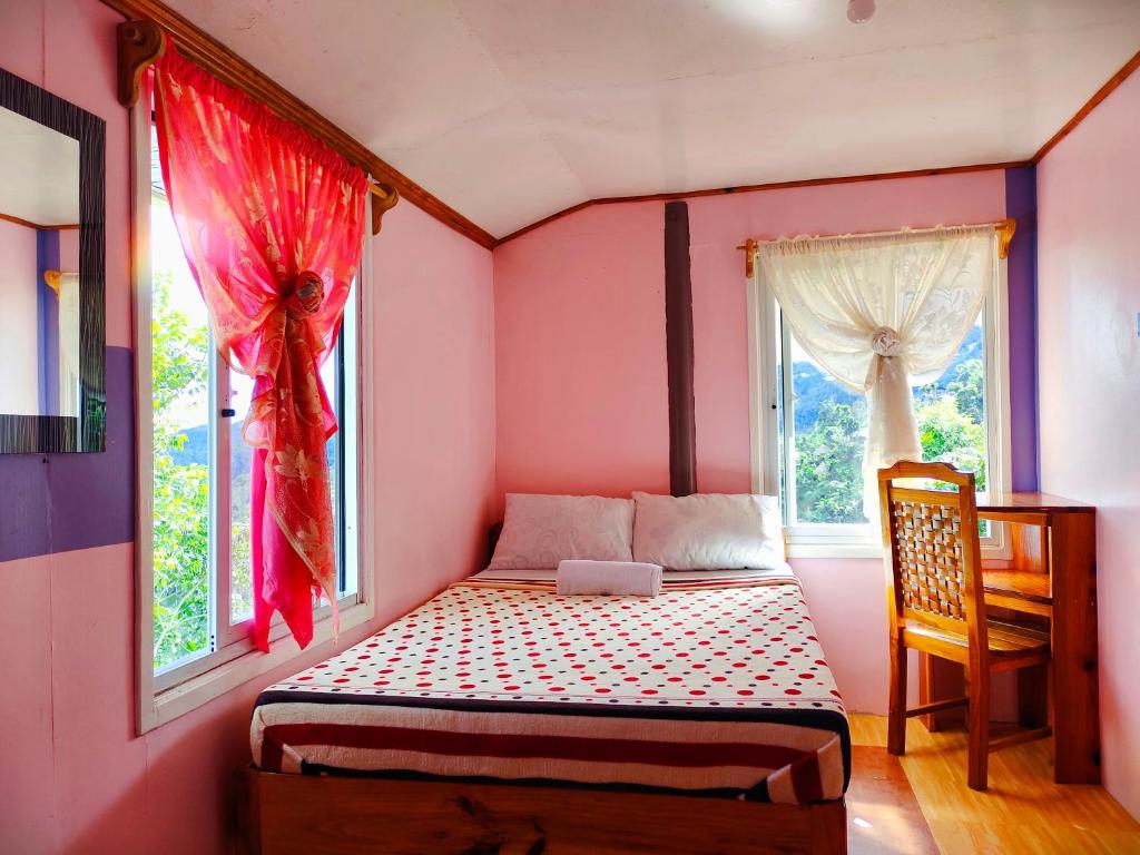 a small bedroom with a bed and two windows at BANAUE EVERGREEN HOSTEL AND RESTAURANT in Banaue