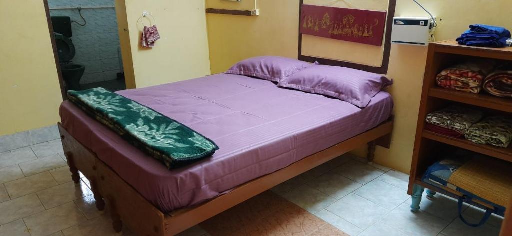 a small bed in a room with purple sheets at Temple Darshan in Chidambaram