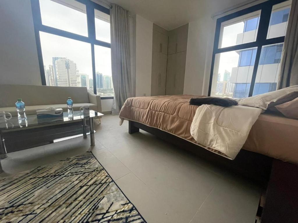 a bedroom with a bed and a table and windows at Adorable Master Room - Heart of Abu Dhabi in Abu Dhabi