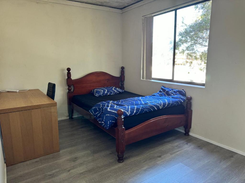 um pequeno quarto com uma cama e uma janela em A private room in a homestay!! em Bankstown