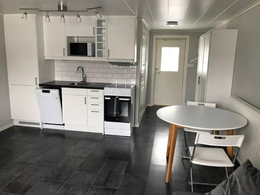 cocina con armarios blancos, mesa y sillas en Lägenhet med uteplats, en Karlskoga