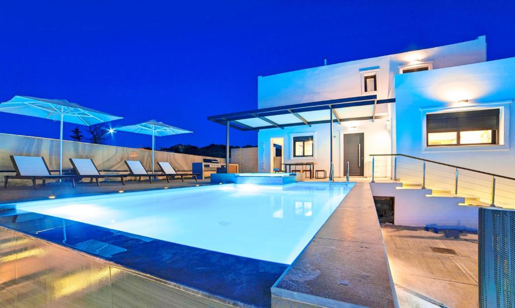 a villa with a swimming pool at night at Perla Villas with Heated Pool in Kávallos
