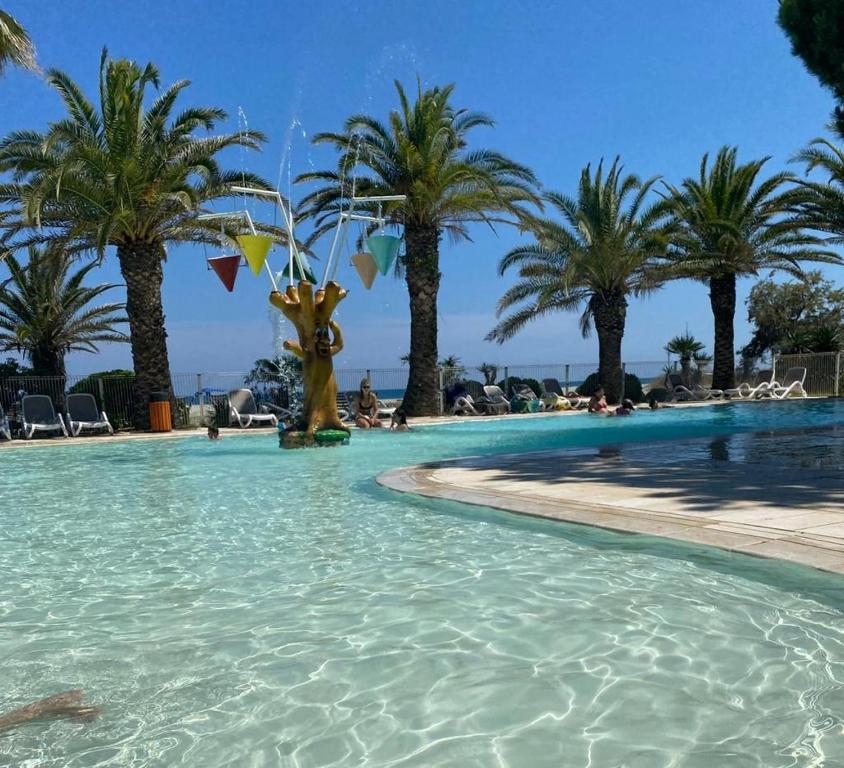 una piscina con palmeras en el fondo en CASA MARE, en Ghisonaccia