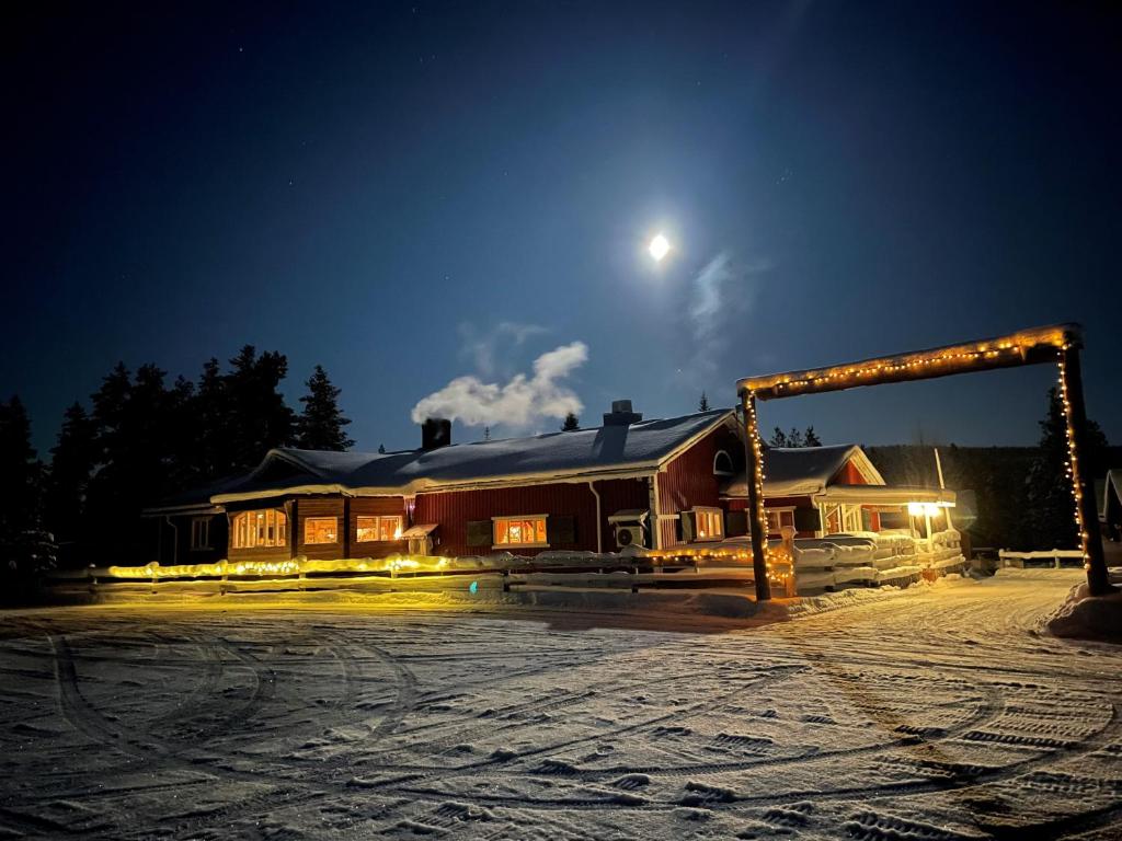 une maison la nuit avec la lune dans le ciel dans l'établissement Skogen-Lodge, à Koskullskulle