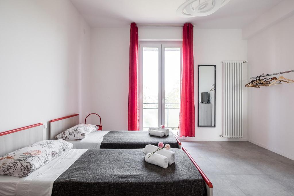 2 camas en un dormitorio con cortinas rojas en Bologna Accommodation Fiera 2 Checkin Automatico - Aperti H24 en Bolonia