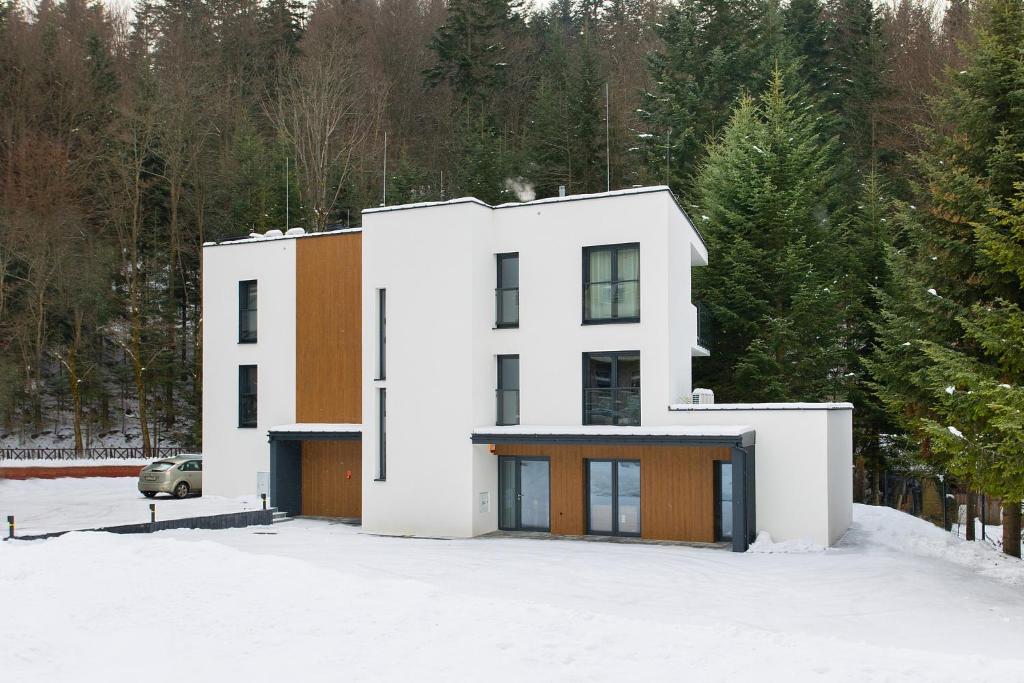 a white house in the snow with trees at PARK APARTAMENTY Krynica Zdrój in Krynica Zdrój