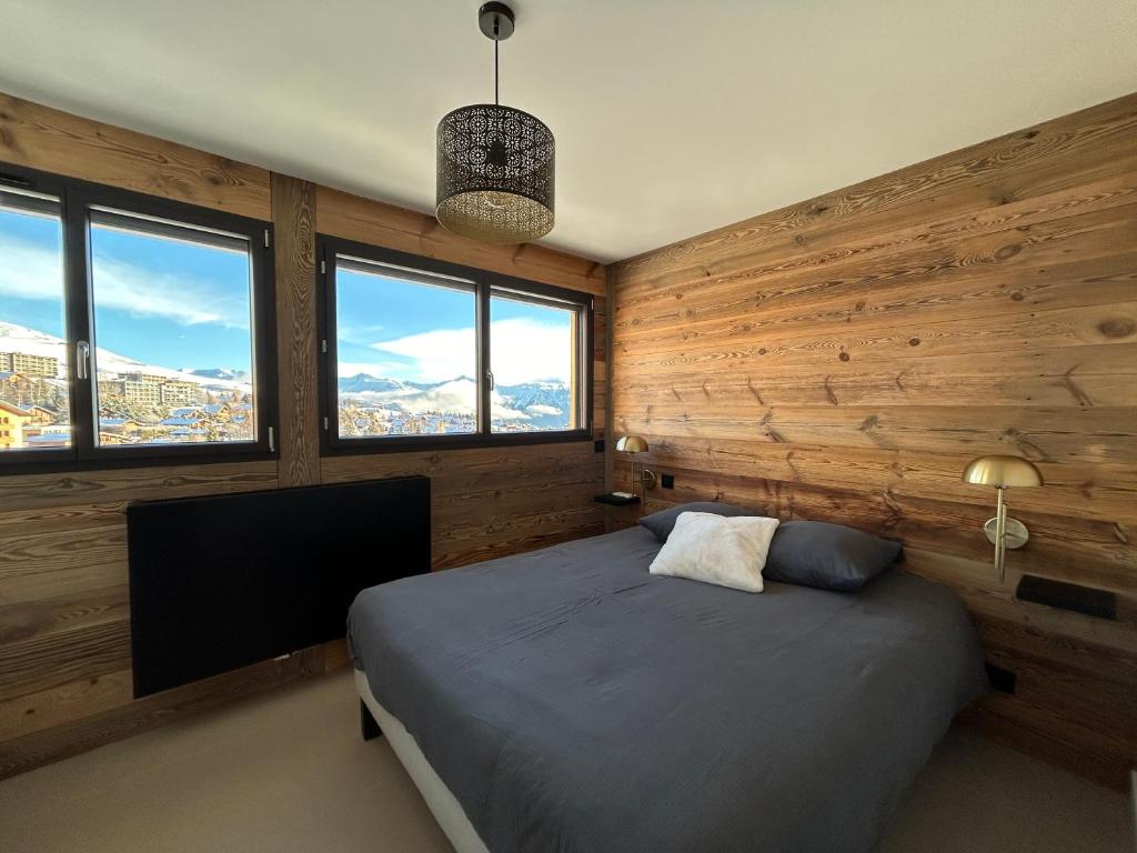 - une chambre dotée de murs en bois et d'un lit avec une télévision dans l'établissement Le Marlou, à La Toussuire