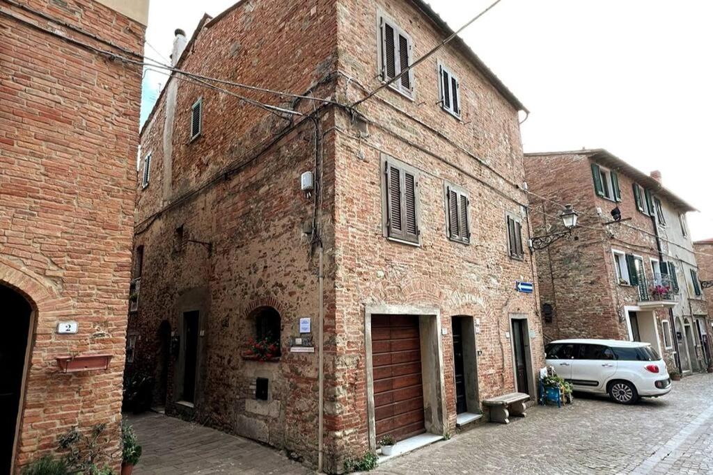 un vieux bâtiment en brique avec une voiture garée à côté dans l'établissement L'angolo del Barbacane, à Terricciola