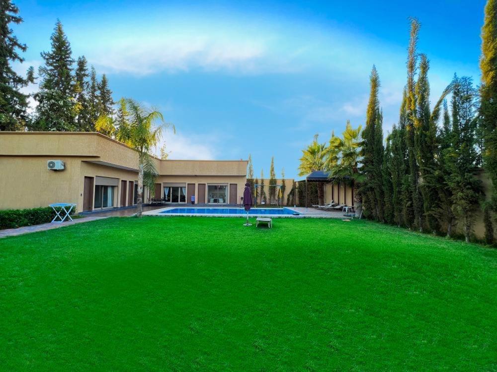 einen großen Garten mit grünem Rasen vor einem Haus in der Unterkunft agafay villa in Marrakesch