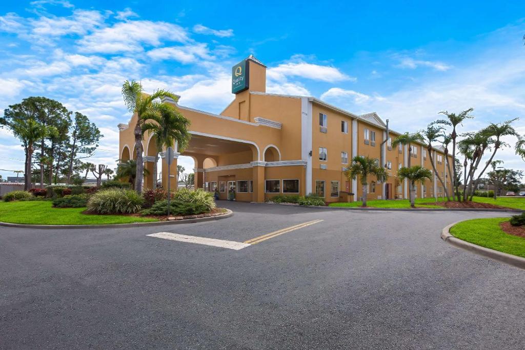 un grand bâtiment avec des palmiers en face d'une route dans l'établissement Quality Inn Sarasota I-75, à Sarasota