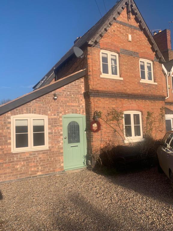 a brick house with a green door in a driveway at Swallows Nest in Gotham